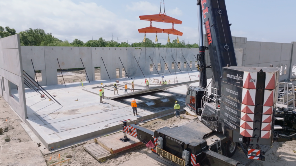Large construction crane lifting up a big slab wall.